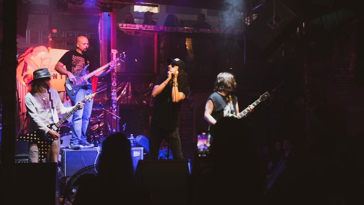 Live band performing on stage under purple and red lighting