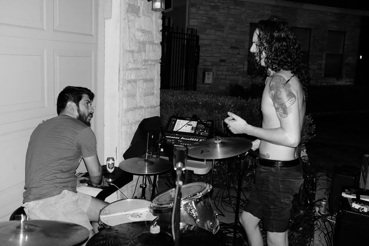 Two musicians performing indoors with drums and keyboard in a black and white photo