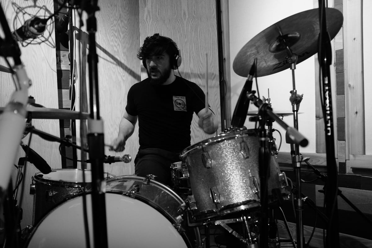 Black and white photo of a drummer playing an electronic drum kit in a studio setting